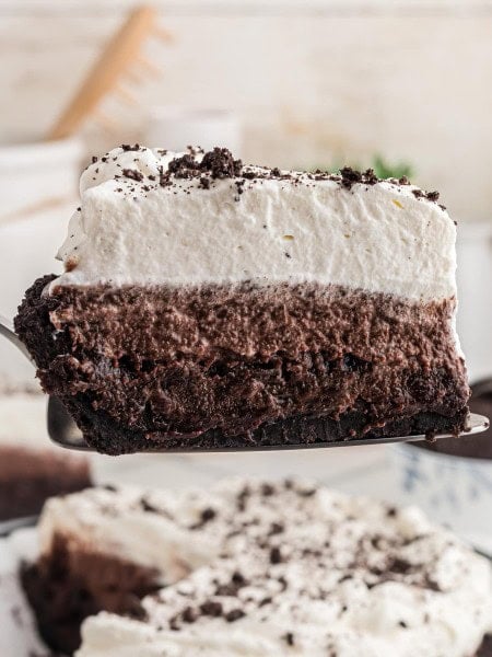 Close-up of a Mississippi Mud Pie slice showing the crust, brownie, mousse, and whipped cream layers.