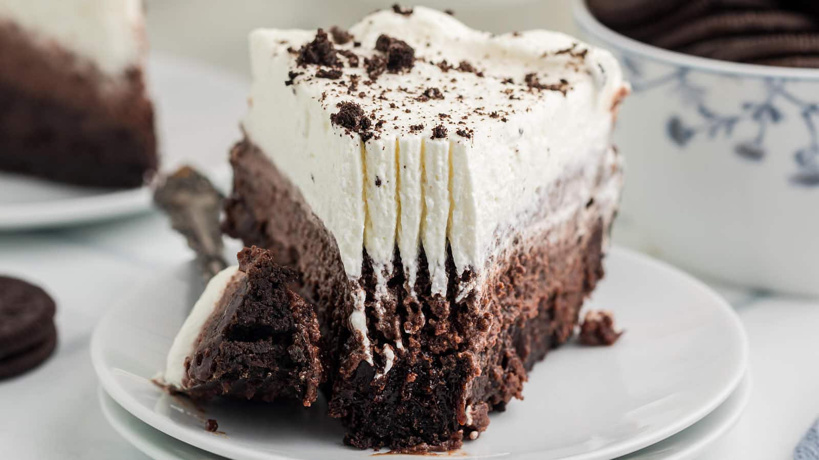 Fork marks in the whipped cream of a Mississippi Mud Pie slice with a bite on the plate.