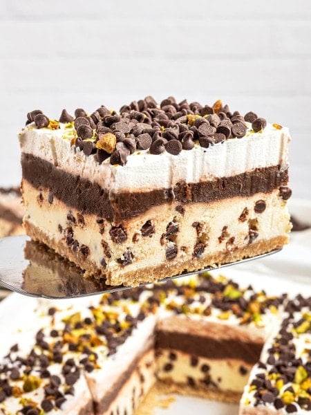 A slice of Cannoli Delight lifted from the baking dish on a serving spatula.