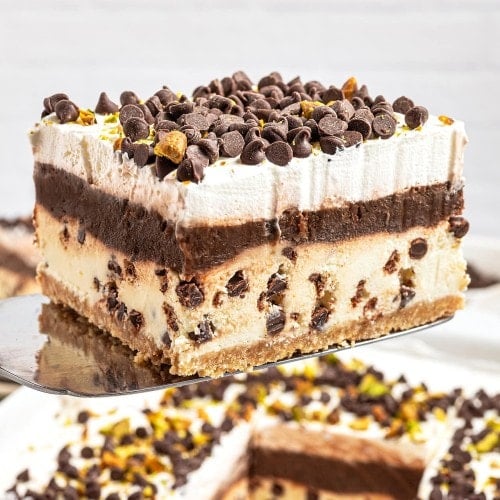 A slice of Cannoli Delight lifted from the baking dish on a serving spatula.