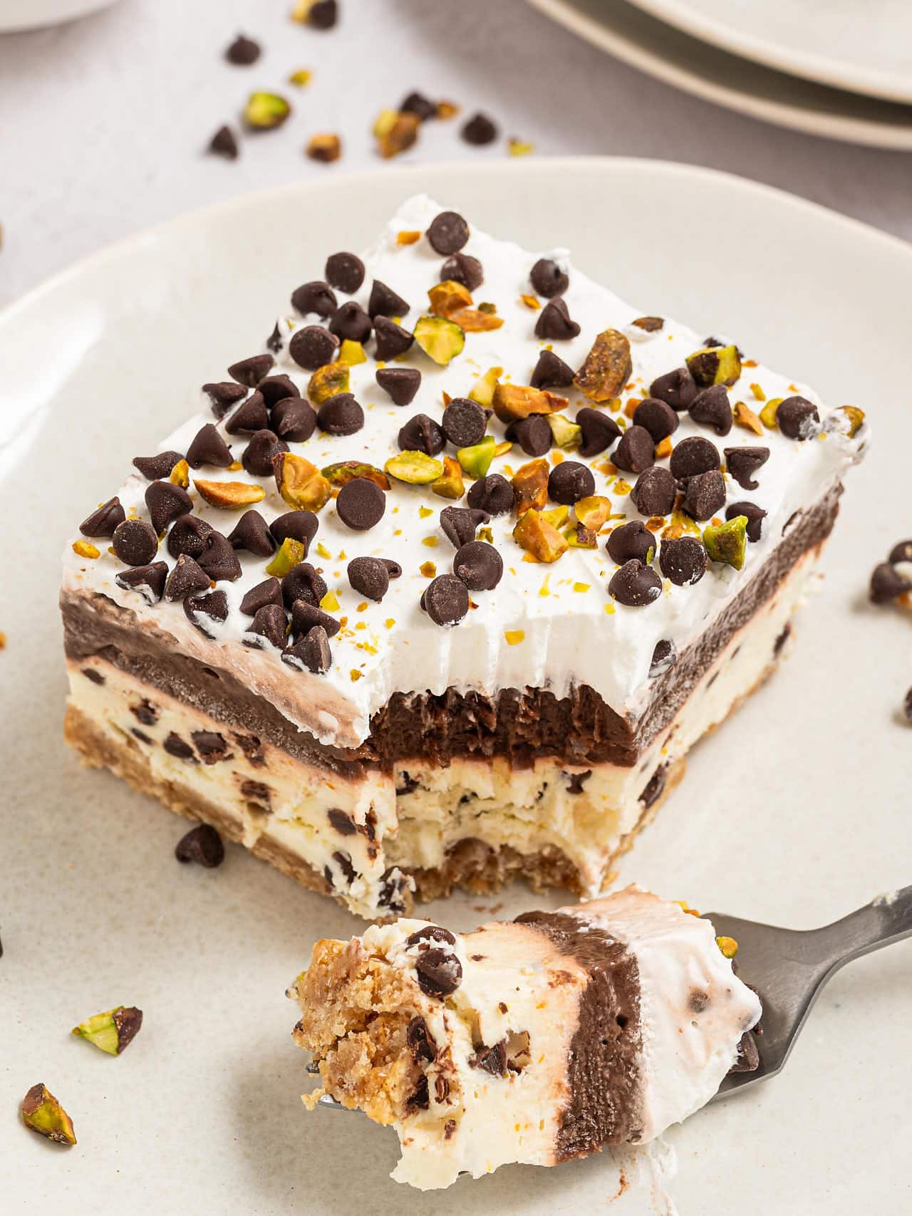 A forkful of Cannoli Delight in front of a slice on a white plate.