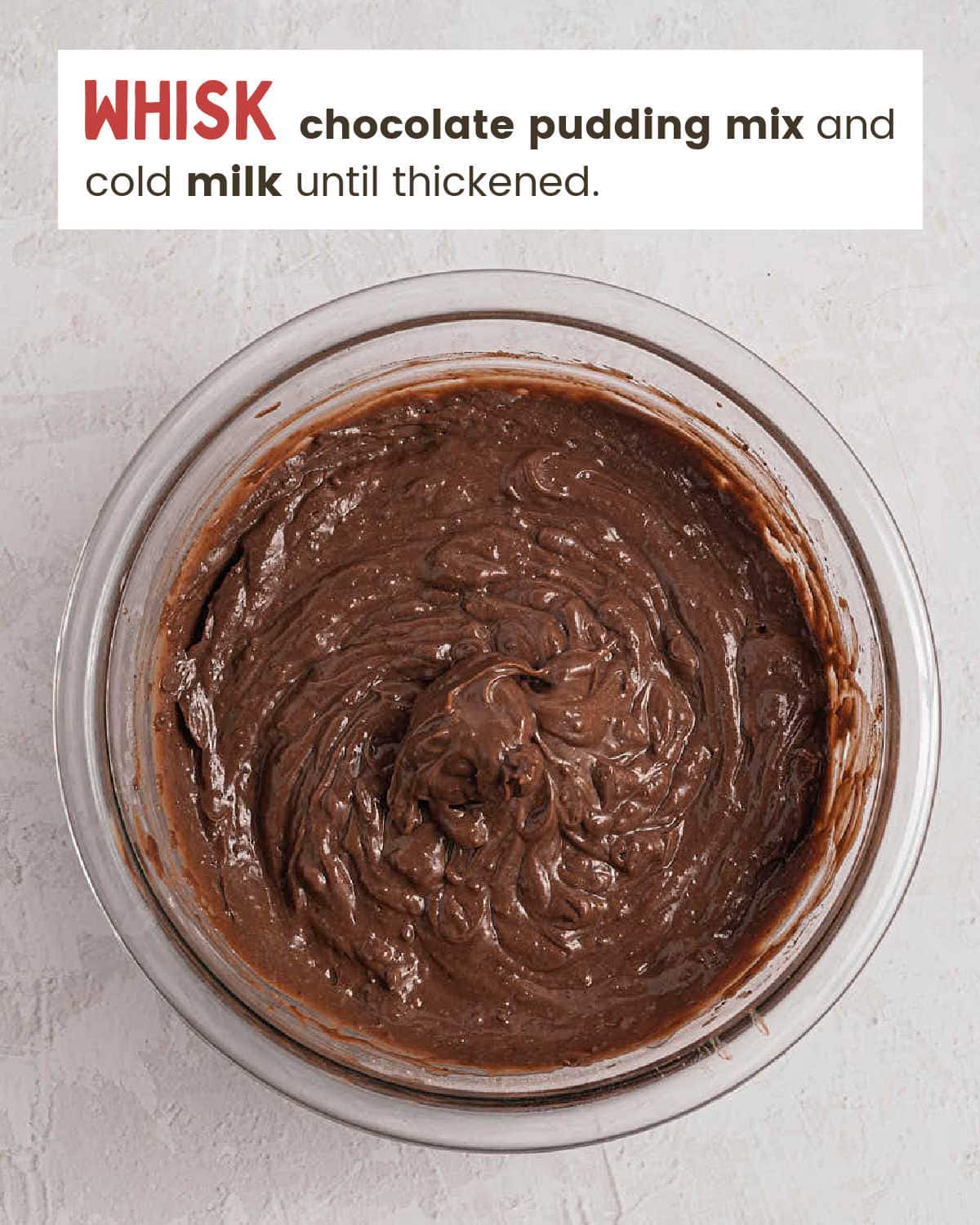 Whisked chocolate pudding in a glass mixing bowl.