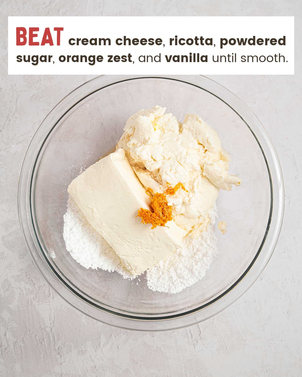 Cream cheese, ricotta, powdered sugar, and orange zest in a glass mixing bowl.