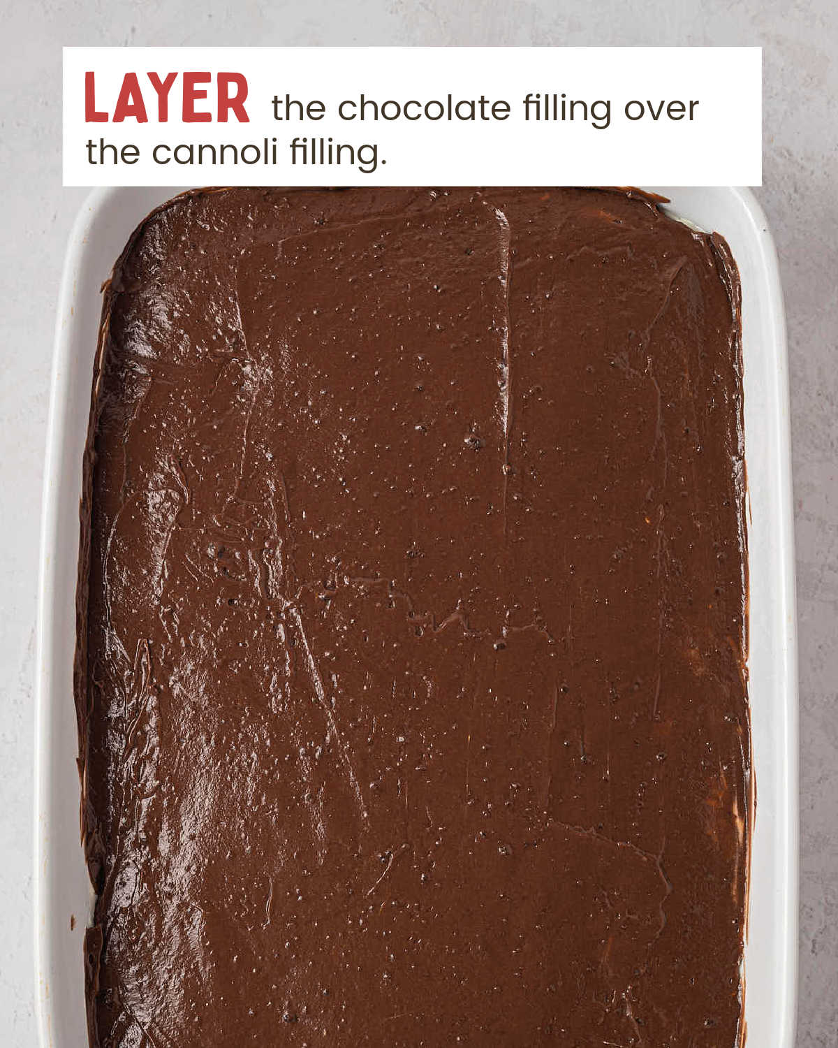 Chocolate pudding layer spread over the cannoli filling in a baking dish.