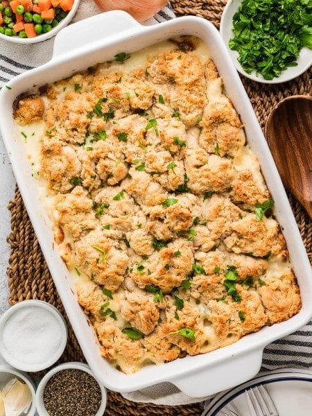 Chicken Cobbler in a white baking dish topped with golden biscuits and fresh parsley.