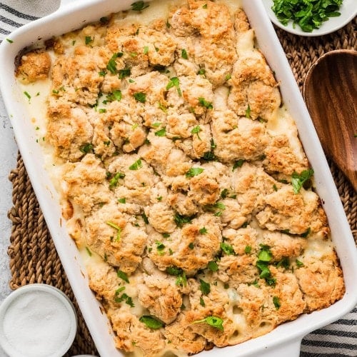 Chicken Cobbler in a white baking dish topped with golden biscuits and fresh parsley.