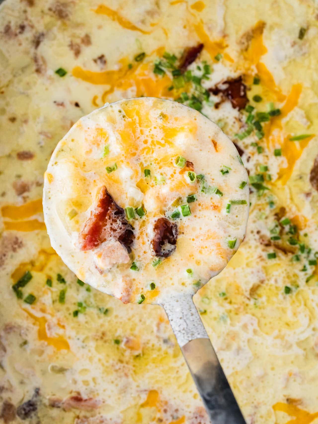 Ladle of Crockpot Loaded Potato Soup held over the slow cooker.