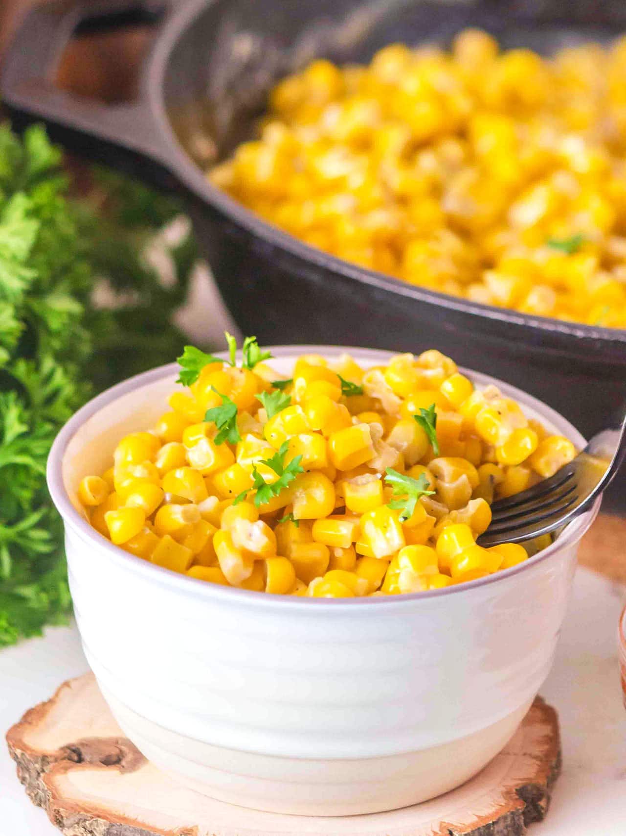 A garnished bowl of Honey Butter Skillet Corn with a fork tucked inside.