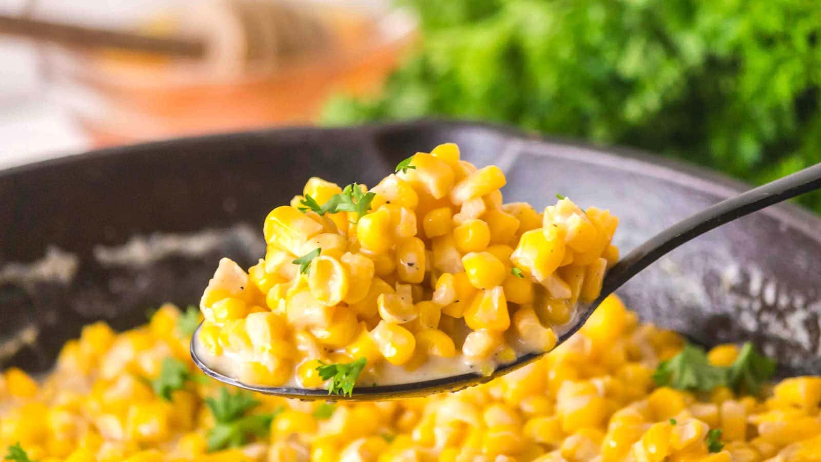 A spoonful of Honey Butter Skillet Corn held above the skillet.