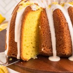 Cake server lifting the first slice from a glazed Lemon Bundt Cake.