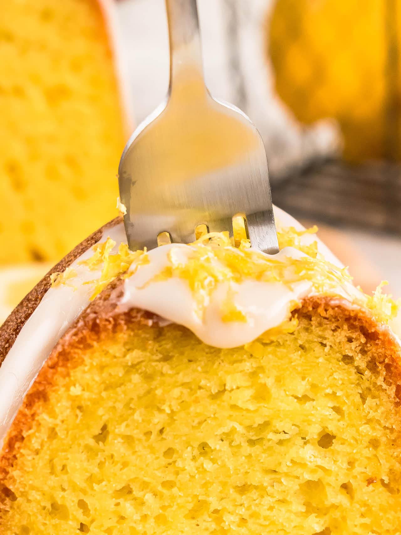 Fork cutting into the glazed top of a Lemon Bundt Cake slice.