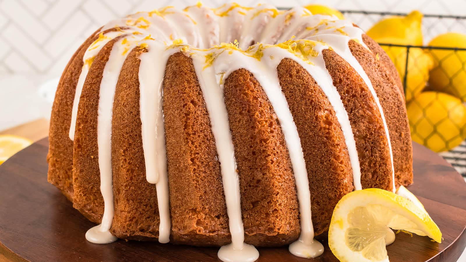 Glazed Lemon Bundt Cake with fresh lemons on a wooden board.
