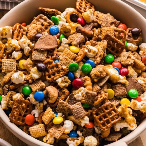 Sweet and Salty Chex Mix in a bowl with pretzels, popcorn, cashews, and colorful M&Ms.