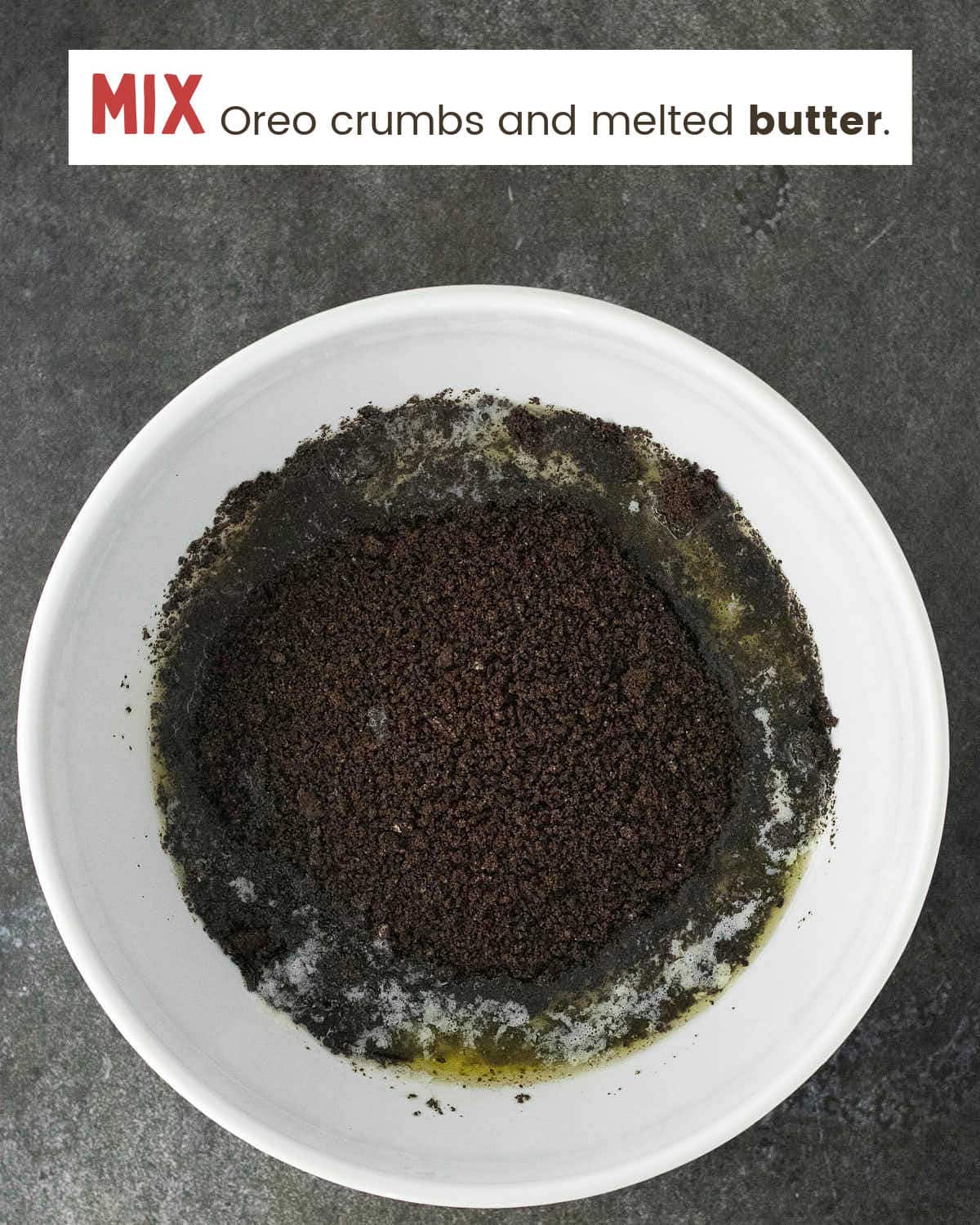 Oreo crumbs and melted butter stirred together in a white bowl.