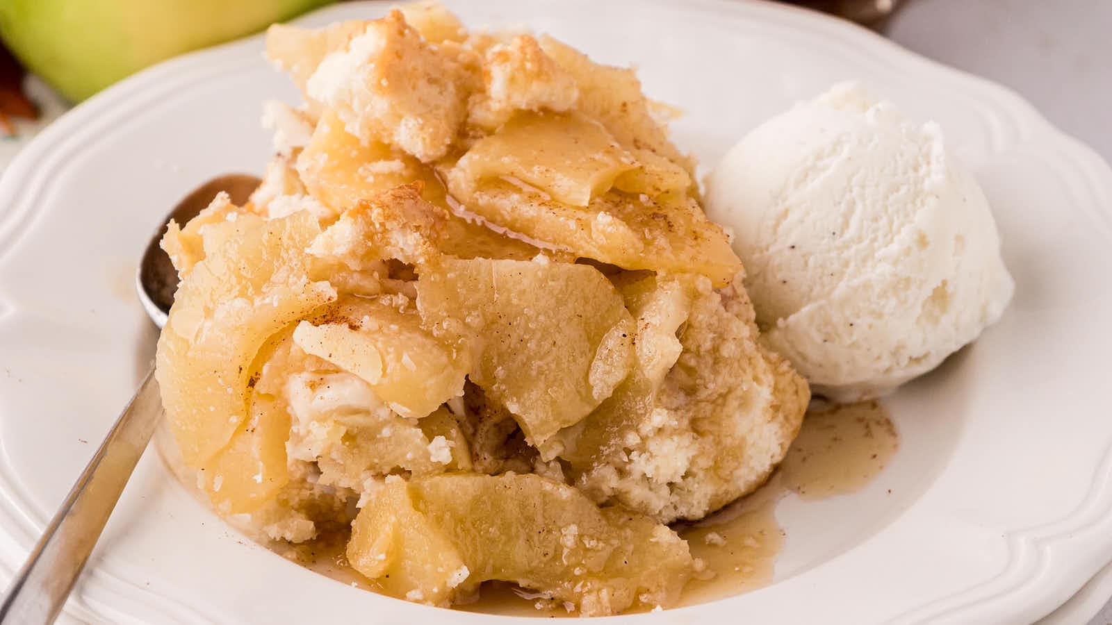 Apple Cobbler served warm in a white bowl with a scoop of vanilla ice cream.