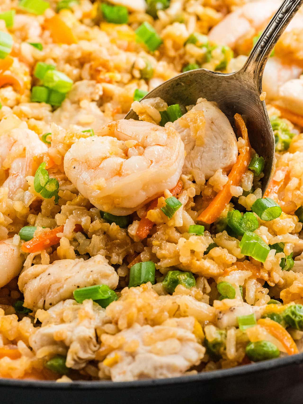 Chicken and Shrimp Fried Rice piled high on a serving spoon over the skillet.