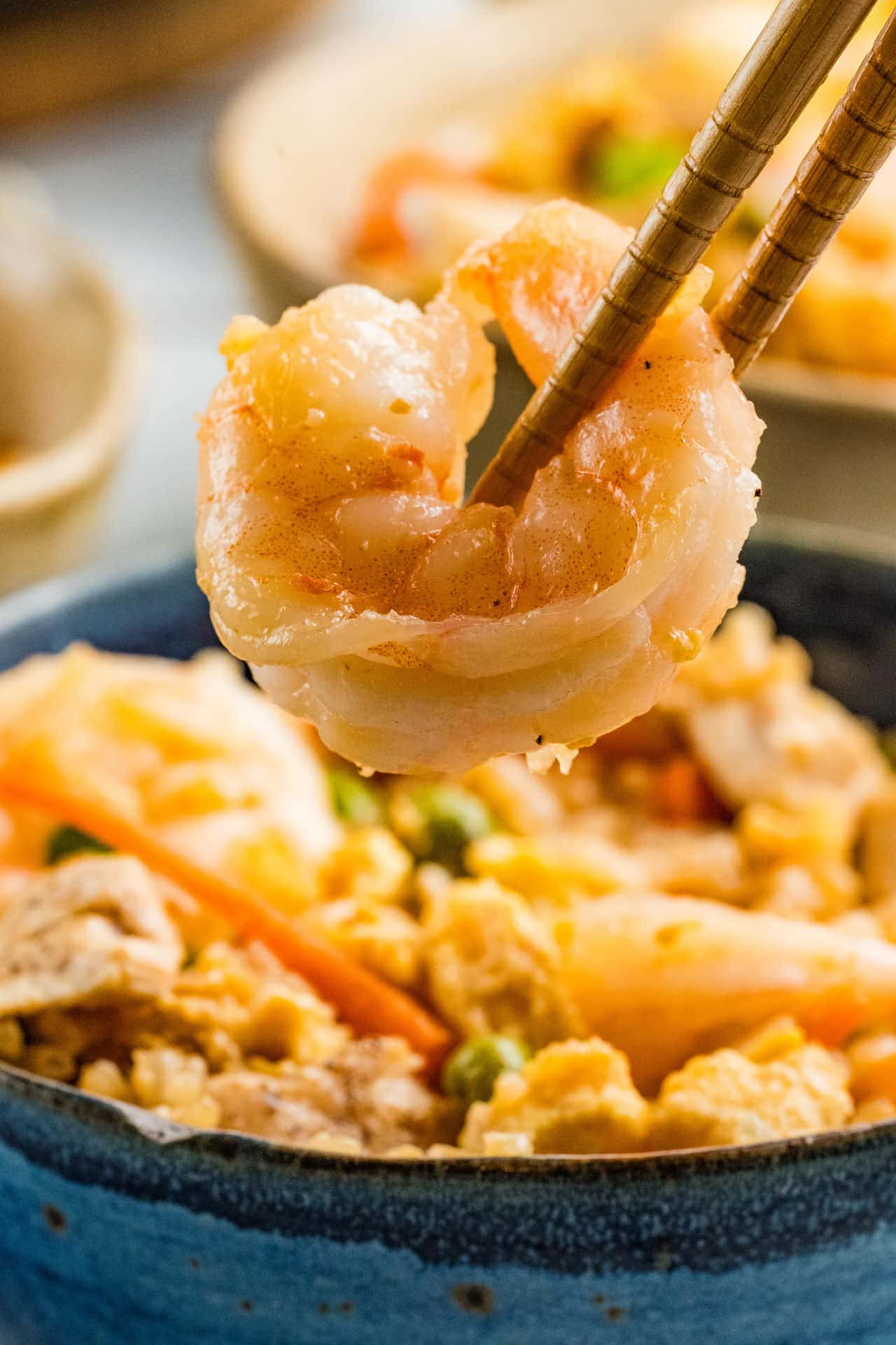 A serving spoon lifting shrimp and chicken with rice from the skillet.