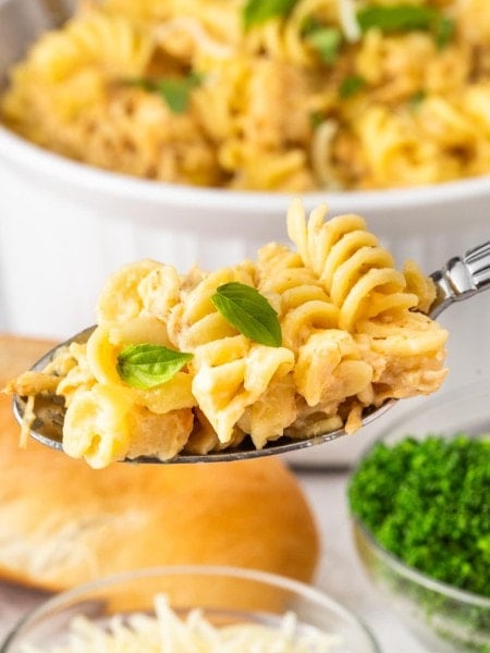 A heaping spoonful of Olive Garden Chicken Pasta held over the serving bowl.