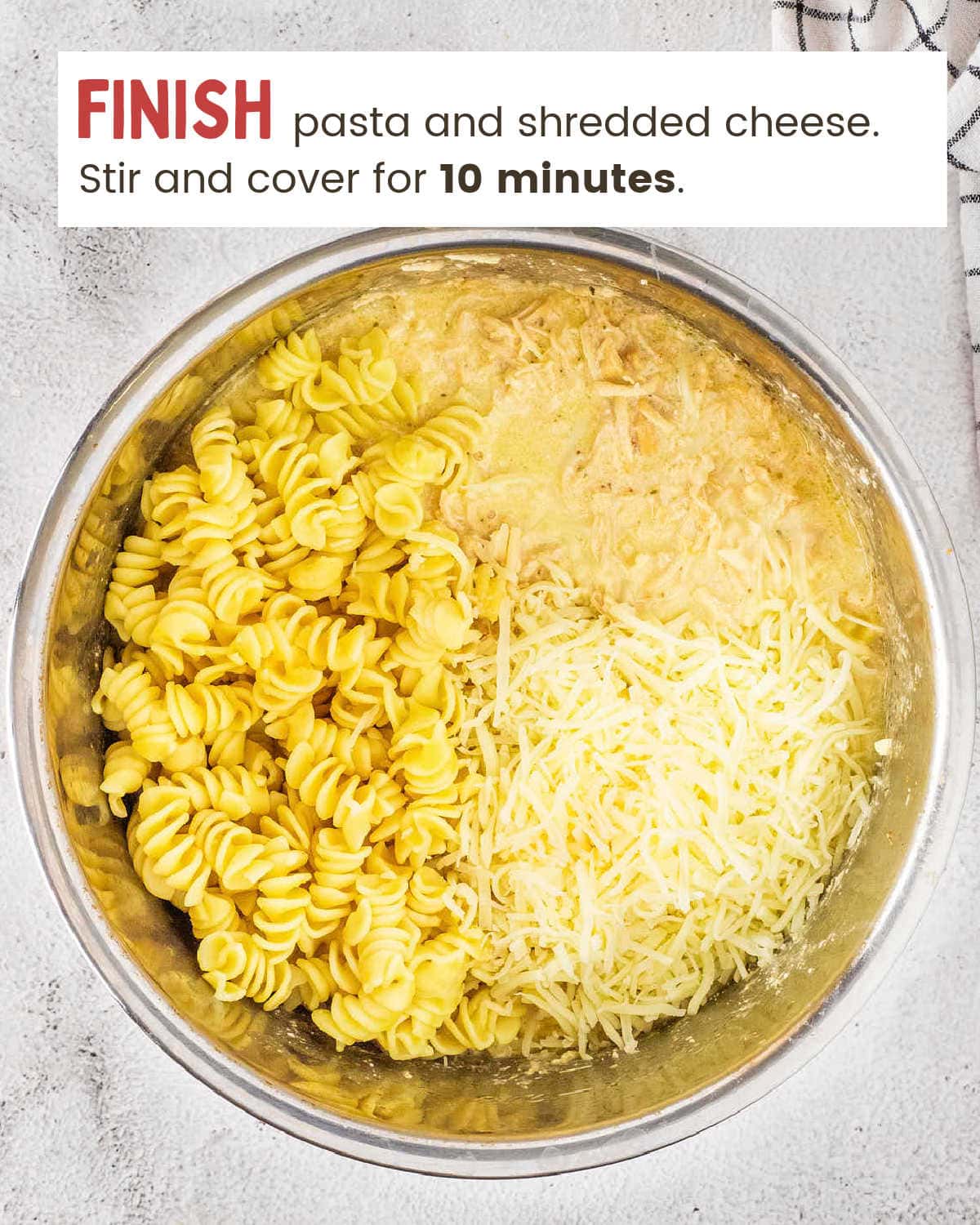 Adding cooked rotini and shredded cheese to the creamy chicken mixture.