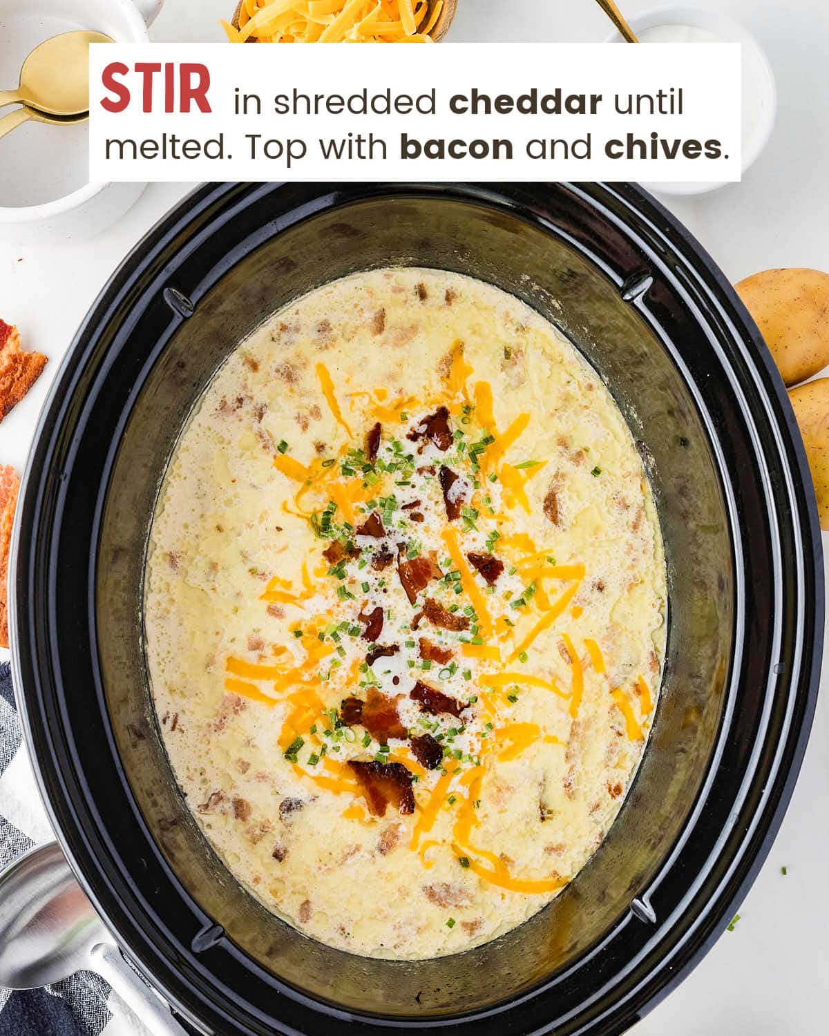 Shredded cheddar, bacon, and chives on top of finished Crockpot Loaded Baked Potato Soup in the slow cooker.