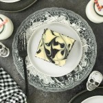 Halloween Cheesecake Bars on a party table with skulls and mini milk bottles.