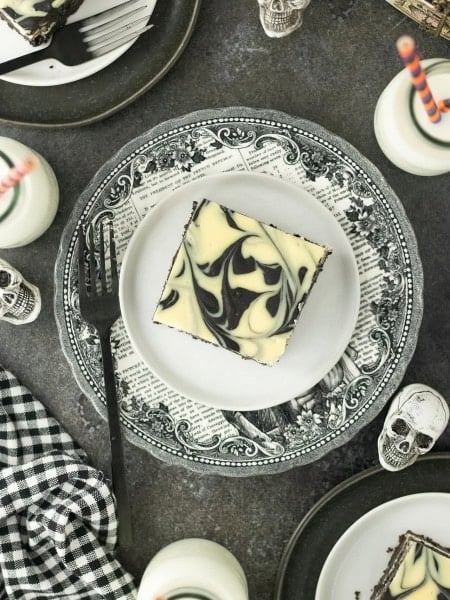 Halloween Cheesecake Bars on a party table with skulls and mini milk bottles.
