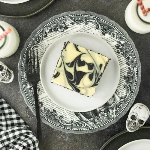 Halloween Cheesecake Bars on a party table with skulls and mini milk bottles.