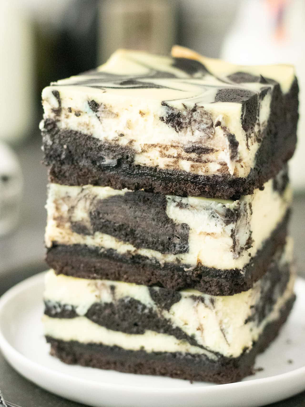 Stacked Oreo cheesecake bars with black and white marbled topping.