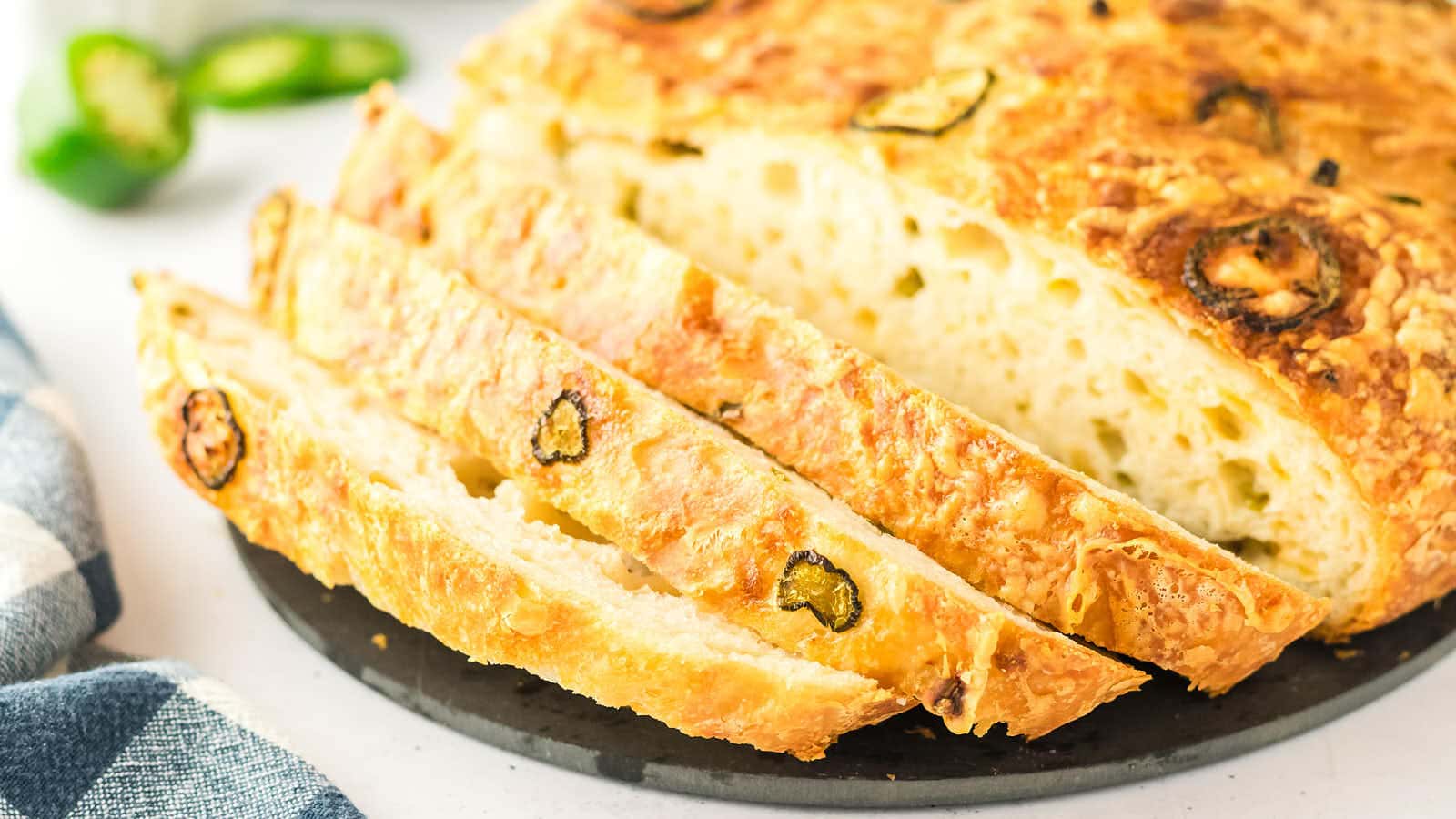 Thick slices of Jalapeño Cheddar Bread fanned out in front of the loaf.