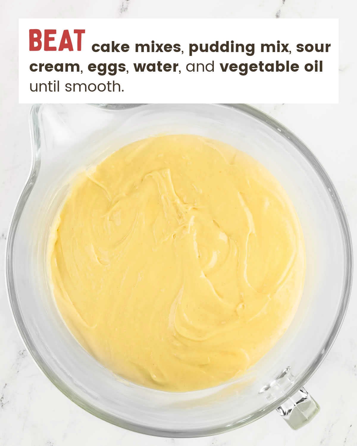 Smooth lemon cake batter ready in a large glass bowl.