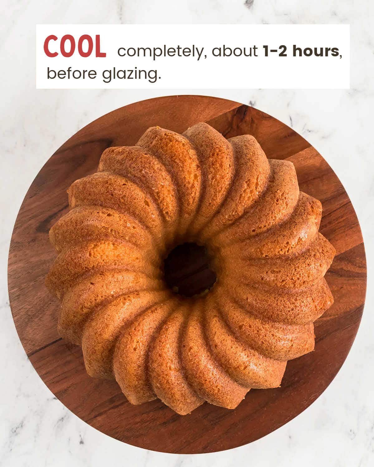 Fluted golden cake released onto a wooden stand before glazing.