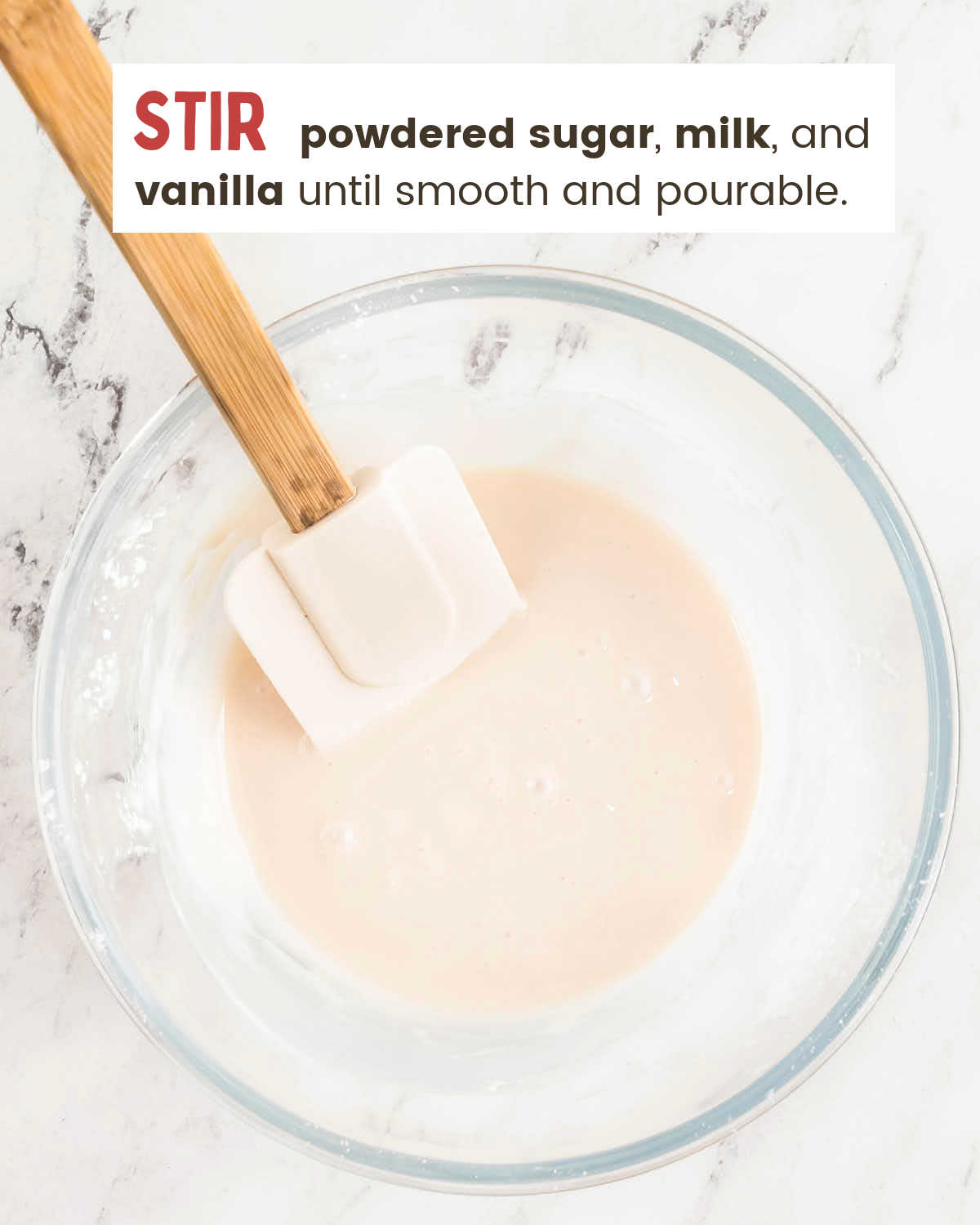 White glaze mixed smooth with a spatula in a glass bowl.