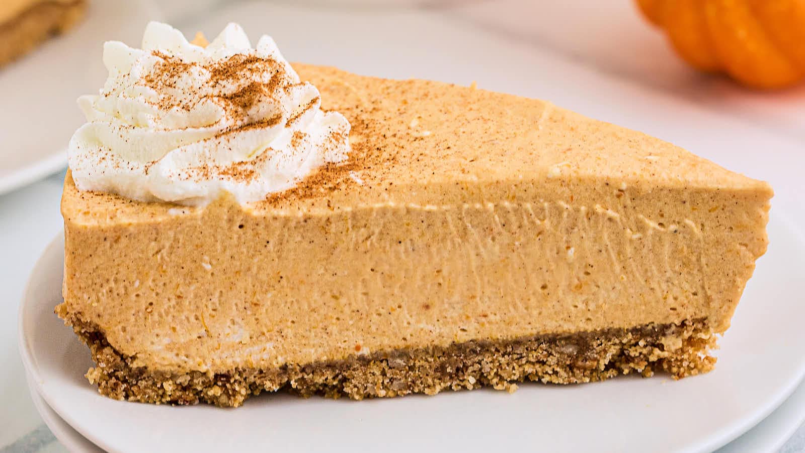 A slice of No Bake Pumpkin Cheesecake on a white plate.