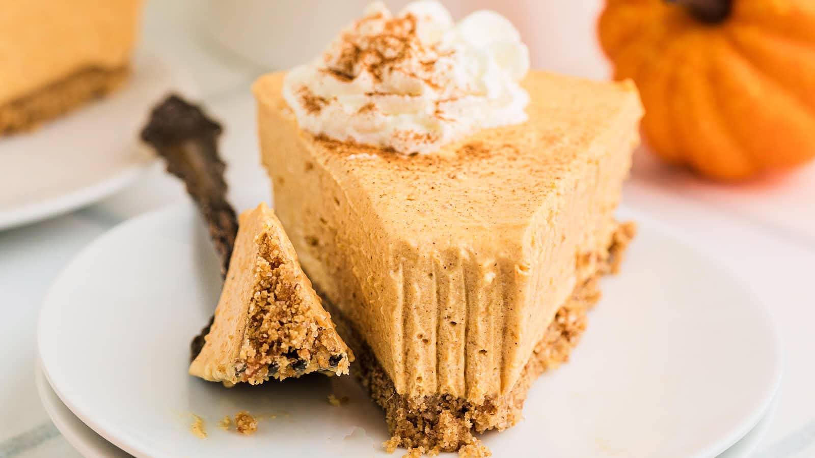 A bite of No Bake Pumpkin Cheesecake on a fork beside the slice.