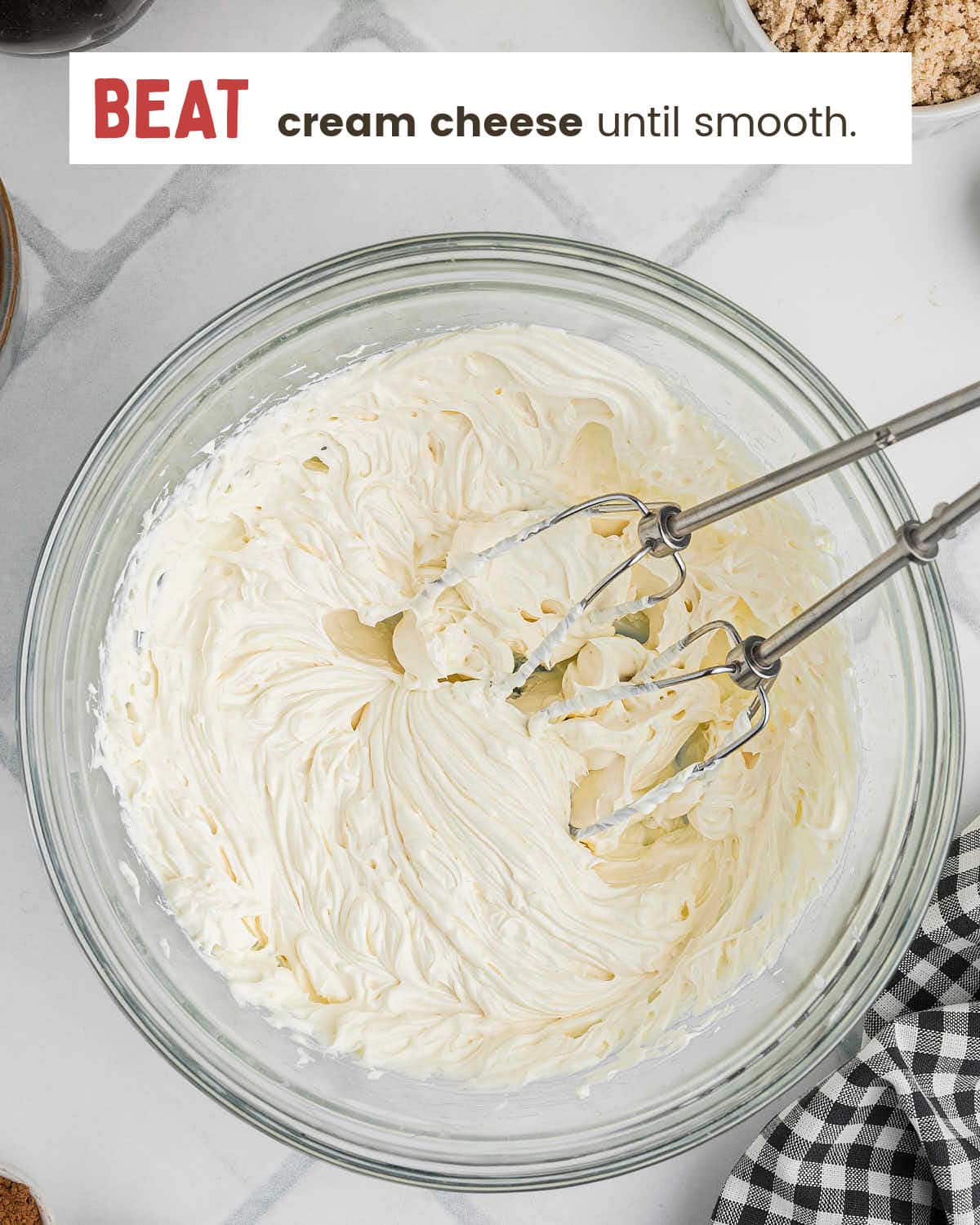 Softened cream cheese beaten smooth in a glass mixing bowl.