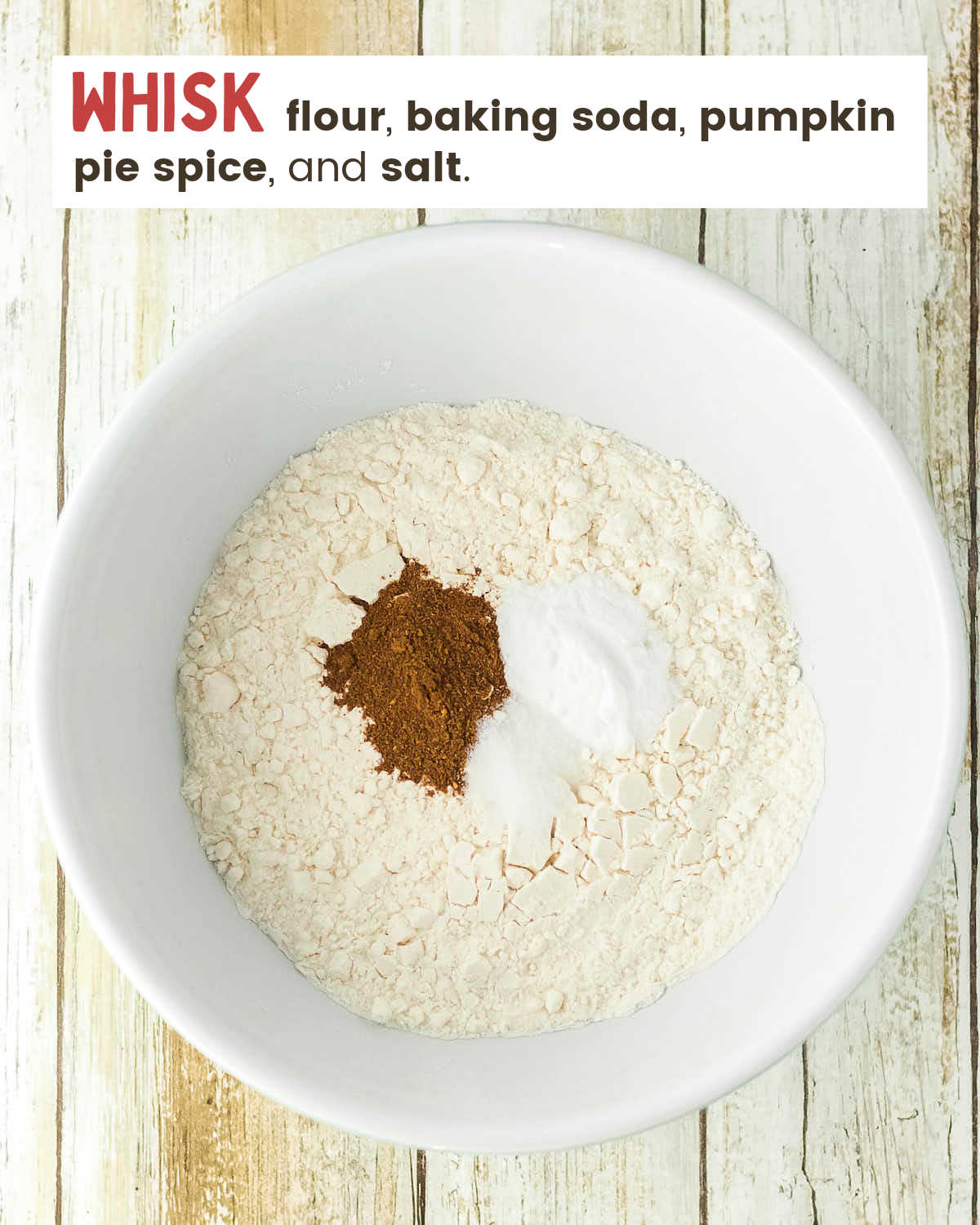 Flour, pumpkin pie spice, baking soda, and salt in a white mixing bowl.