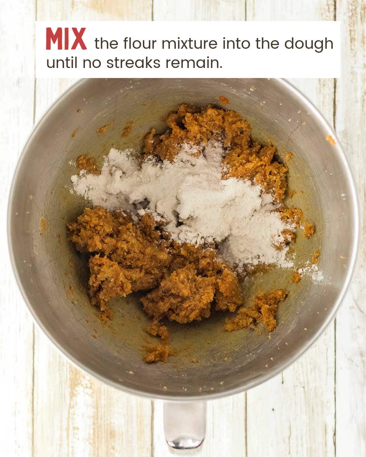 Thick pumpkin cookie dough in a stainless steel mixer bowl.
