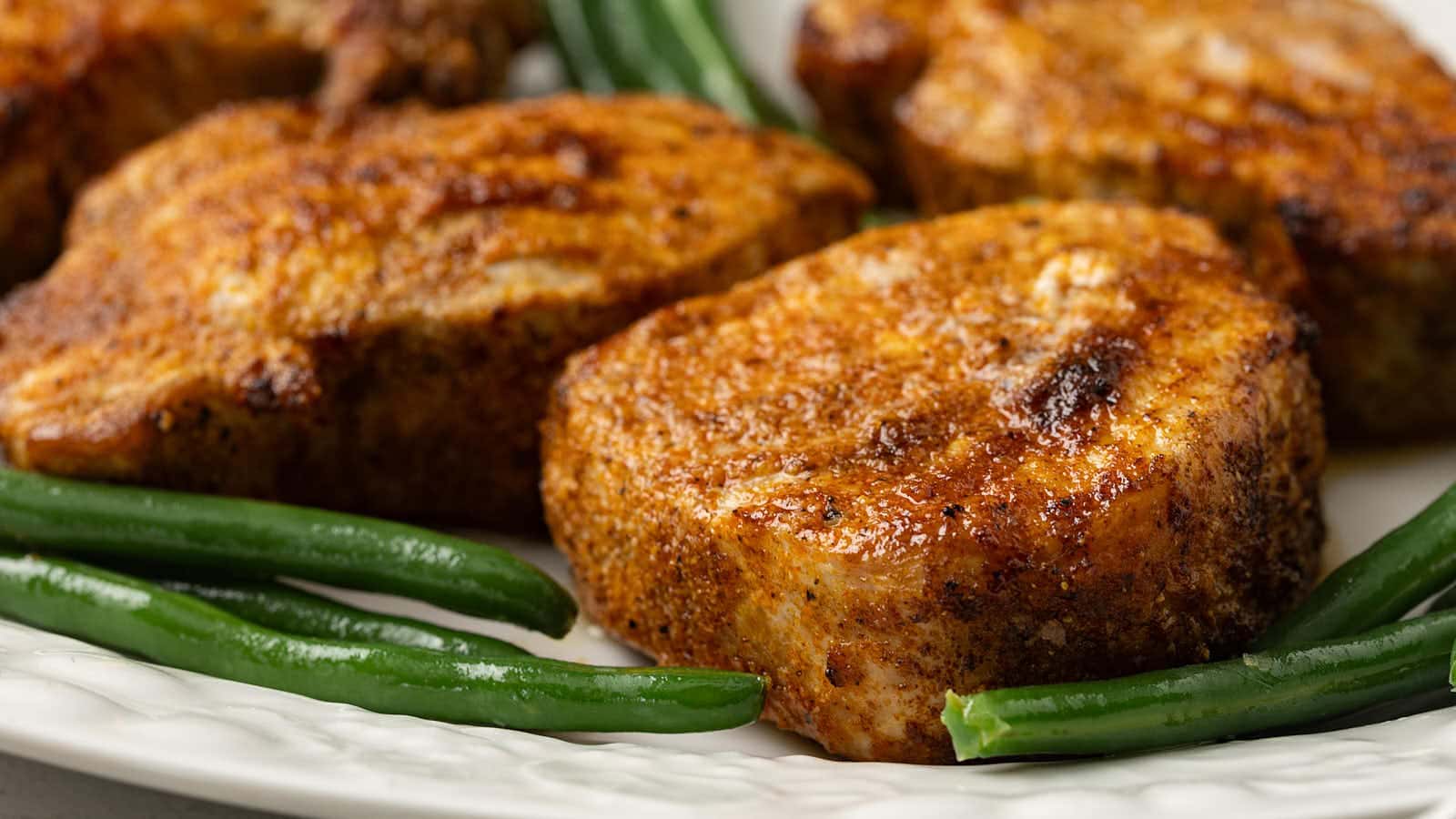 Close-up of juicy Air Fryer Pork Chops with green beans.