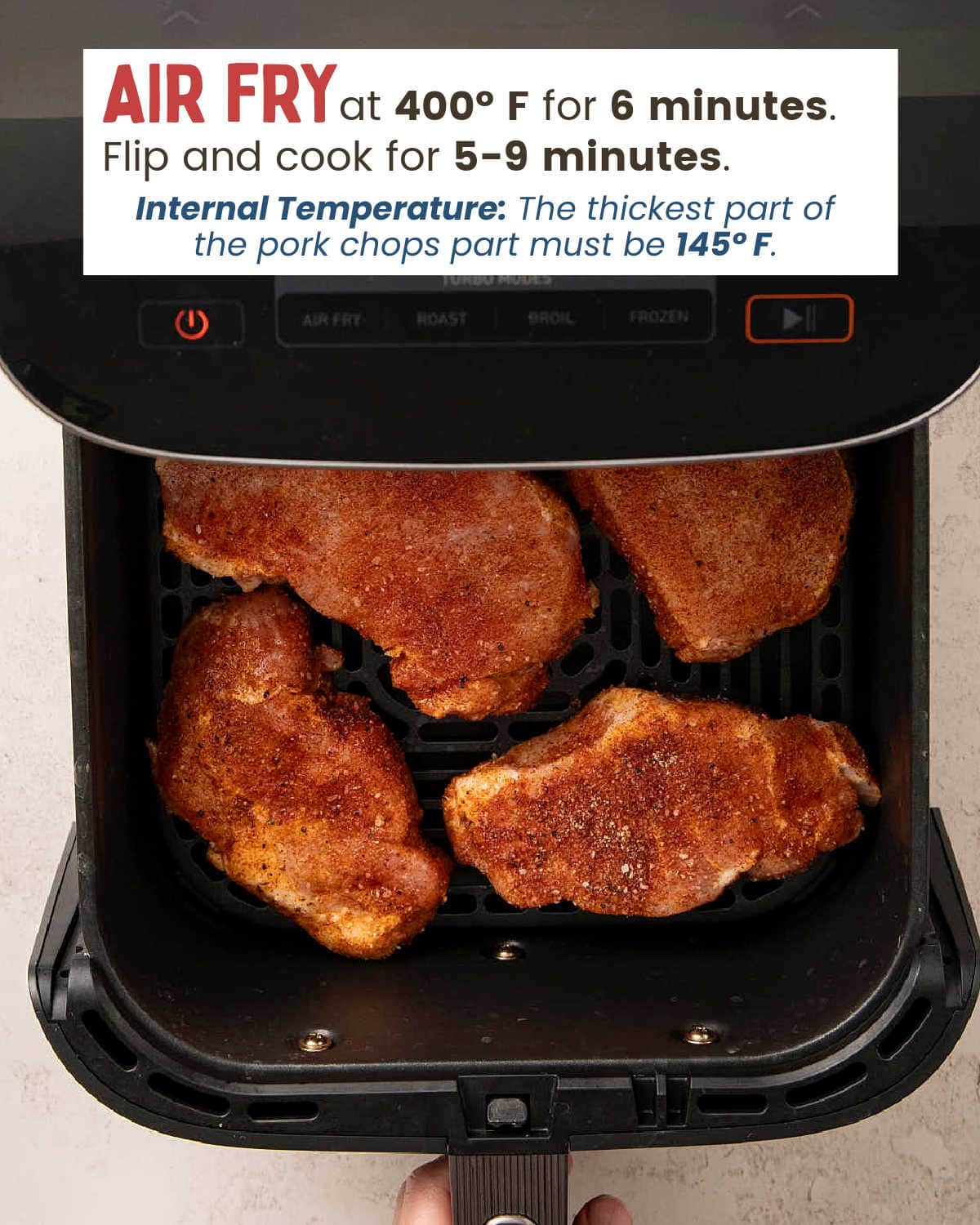 Seasoned pork chops in a single layer in the air fryer basket before cooking Air Fryer Pork Chops.