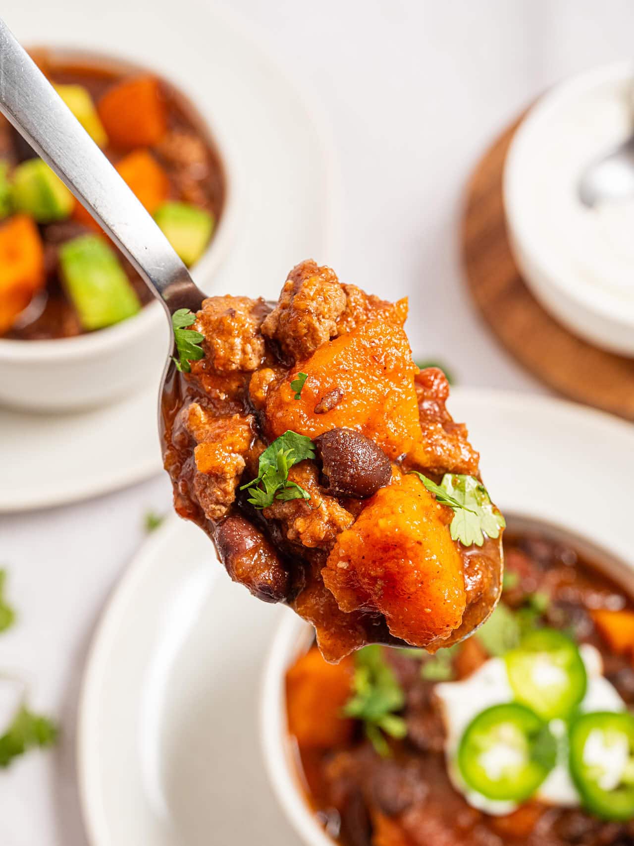 Spoonful of Crockpot Ground Turkey Chili with ground turkey, a sweet potato cube, black beans and cilantro.