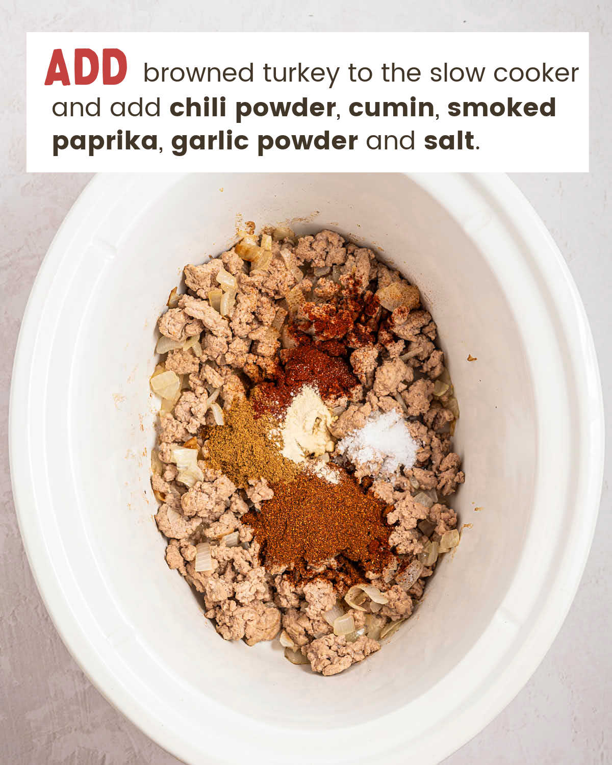 Spices added to browned turkey in a slow cooker for Crockpot Ground Turkey Chili.