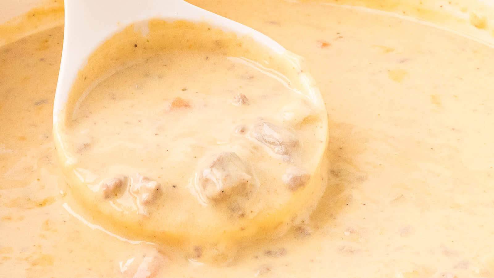 Wide closeup of a ladle resting in a pot of Cheeseburger Soup.