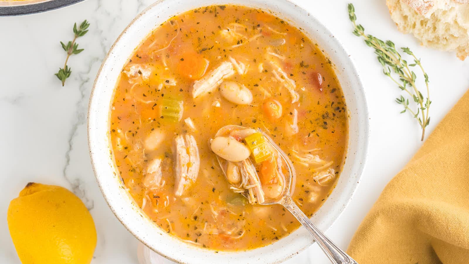 Overhead bowl of Chicken and White Bean Soup with a spoon and lemon.