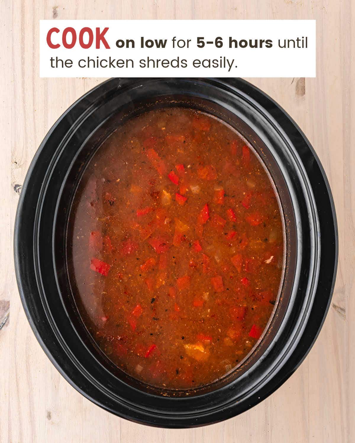 Cooked Crockpot Chicken Enchilada Soup in a black slow cooker before the chicken is shredded.