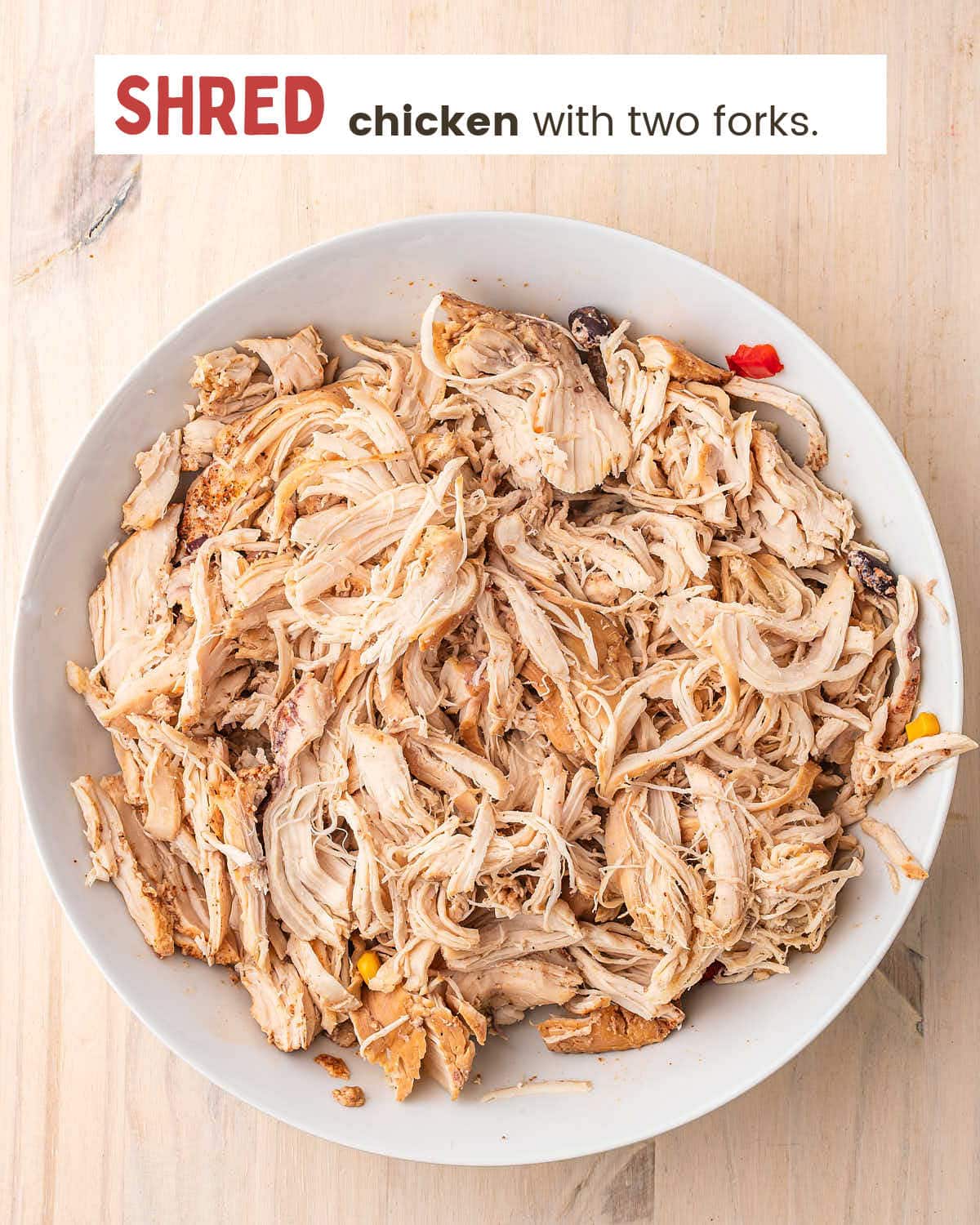 Shredded cooked chicken breast in a white bowl.