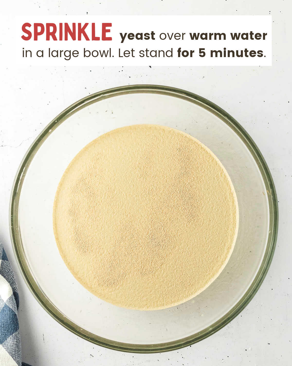 Yeast sprinkled over warm water in a large glass bowl.