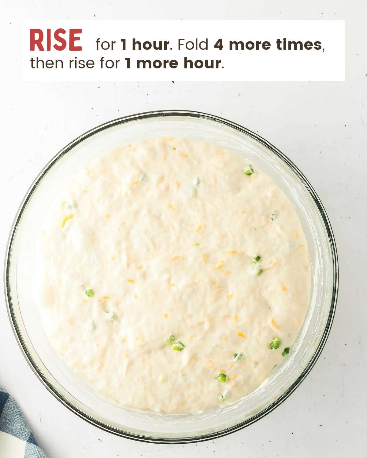 Risen Jalapeño Cheddar Bread dough filling the glass mixing bowl.