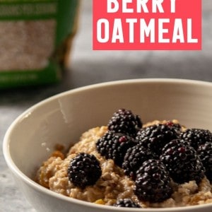 A bowl of berry oatmeal with blackberries, crushed pecans, and maple syrup and a bag of steel cut oats