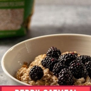 A bowl of berry oatmeal with blackberries, crushed pecans, and maple syrup and a bag of steel cut oats