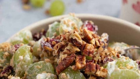 A bowl full of Grape Salad with cranberries and Graham Crackers
